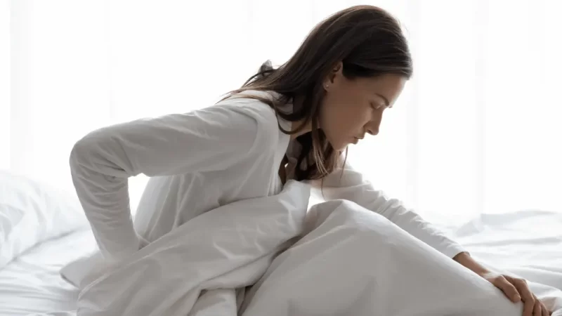 mulher na cama sofrendo com dor devido a hérnia de disco
